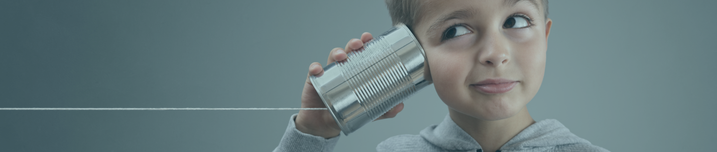 Boy with a can next to his ear with a string using it like a telephone