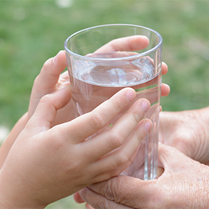children's hands holding a glass of clear water