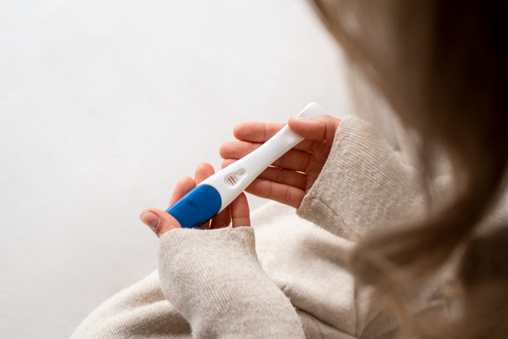 A person holding a pregnancy test showing a positive result with two red lines.