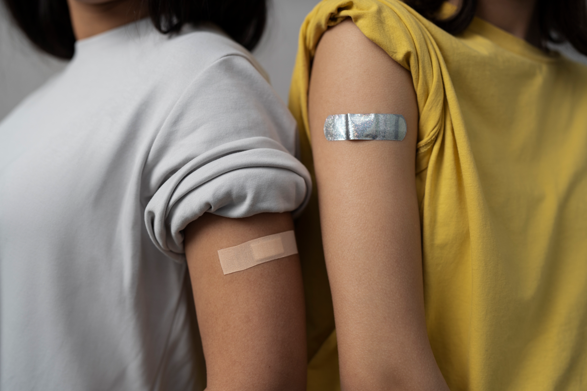 Two arms showing adhesive bandages after vaccination